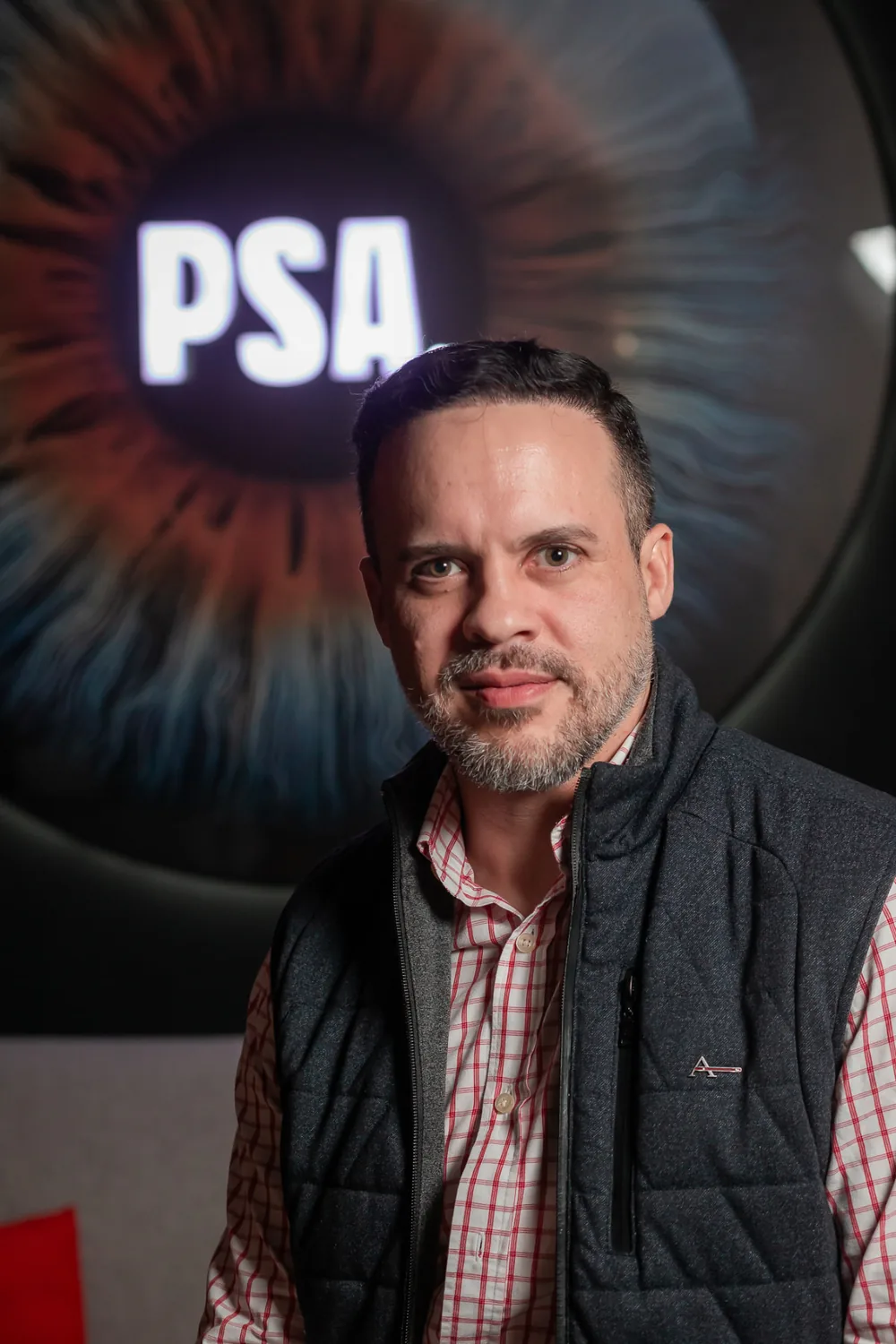 Retrato de Gabriel Pavão em ambiente de estúdio, com arte de íris iluminada ao fundo.