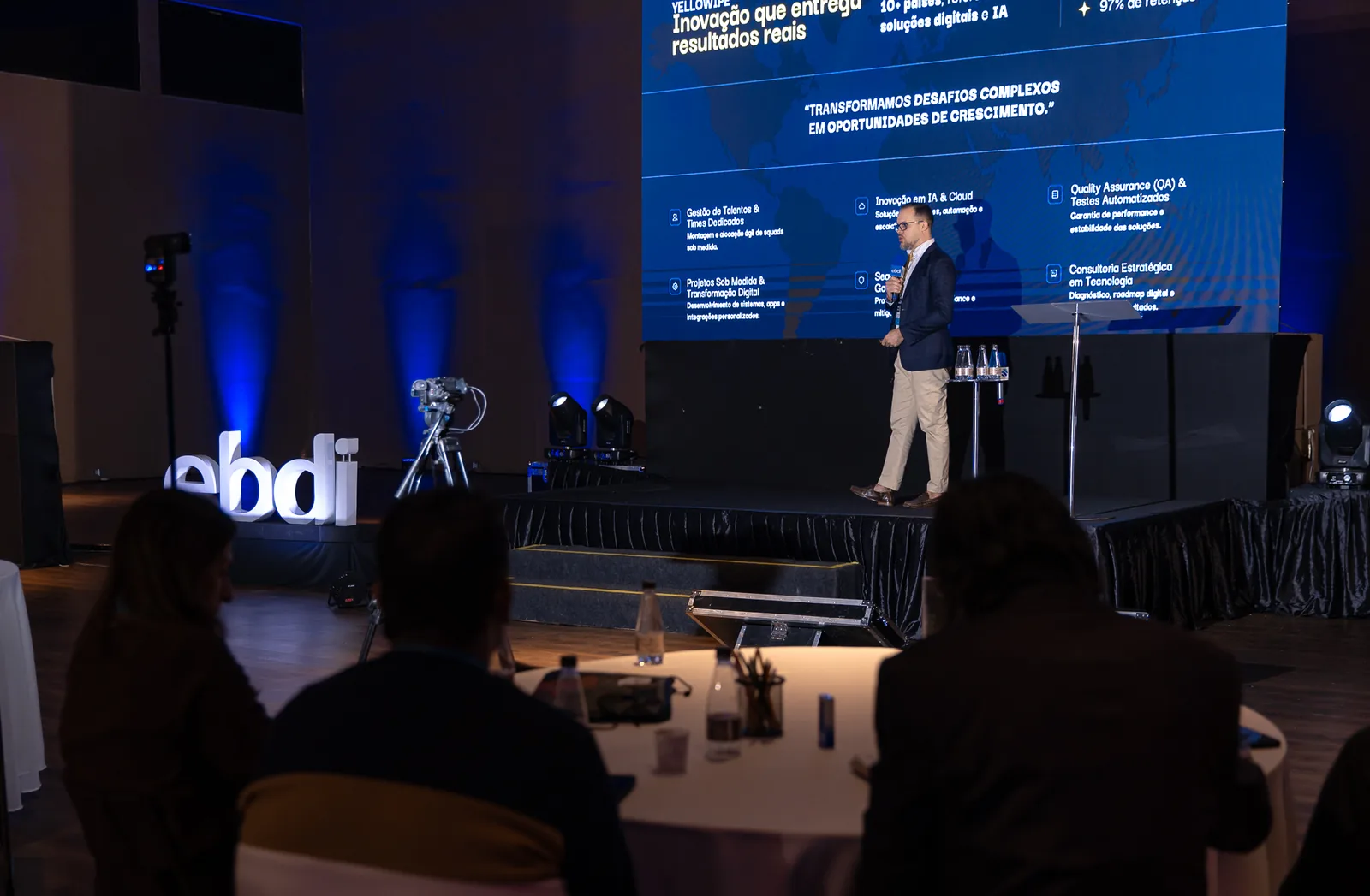 Gabriel Pavão apresentando no palco do EBDI com slide sobre inovação e IA projetado ao fundo.